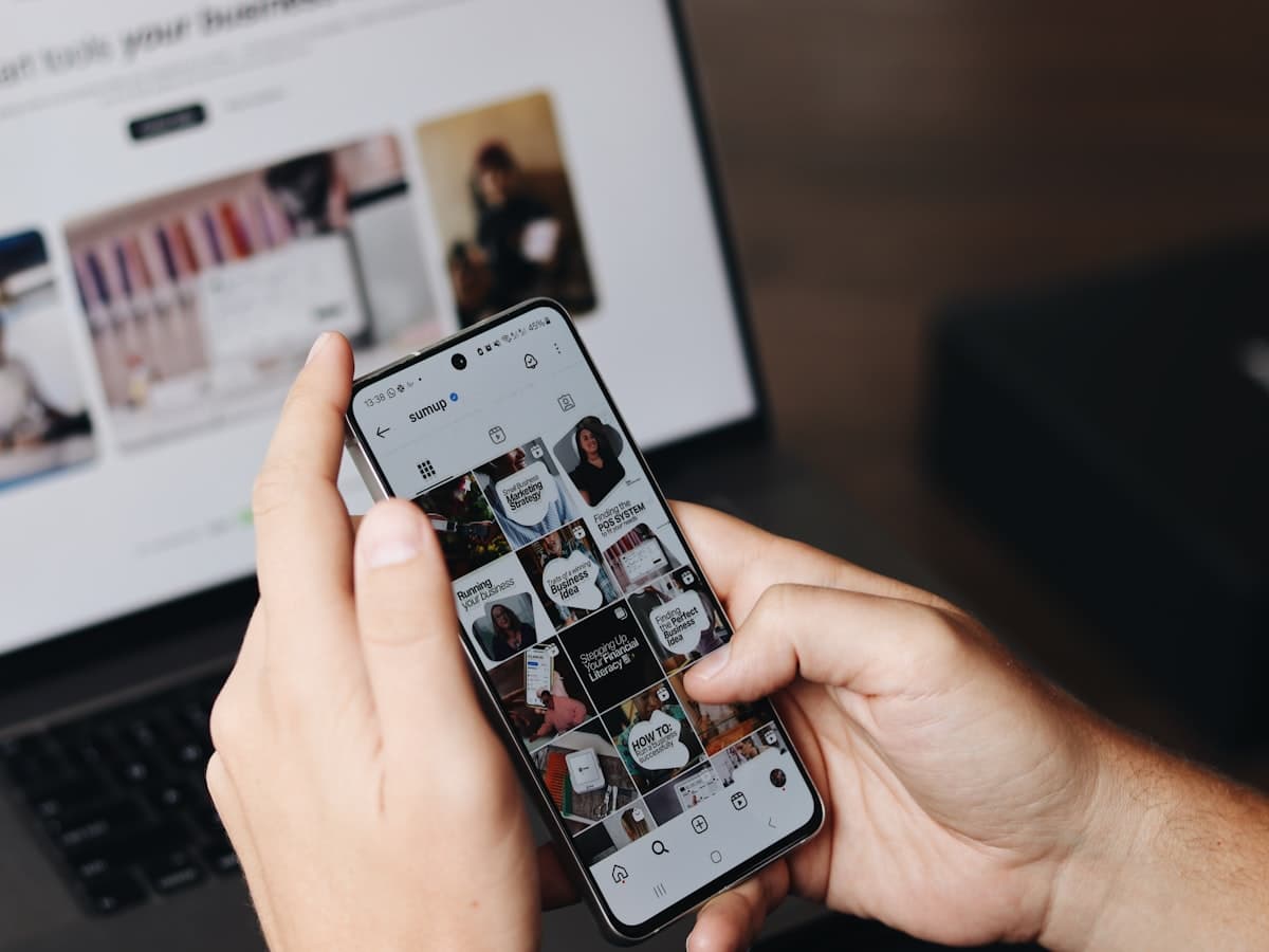 Reviewing social ad creative on a phone beside a laptop