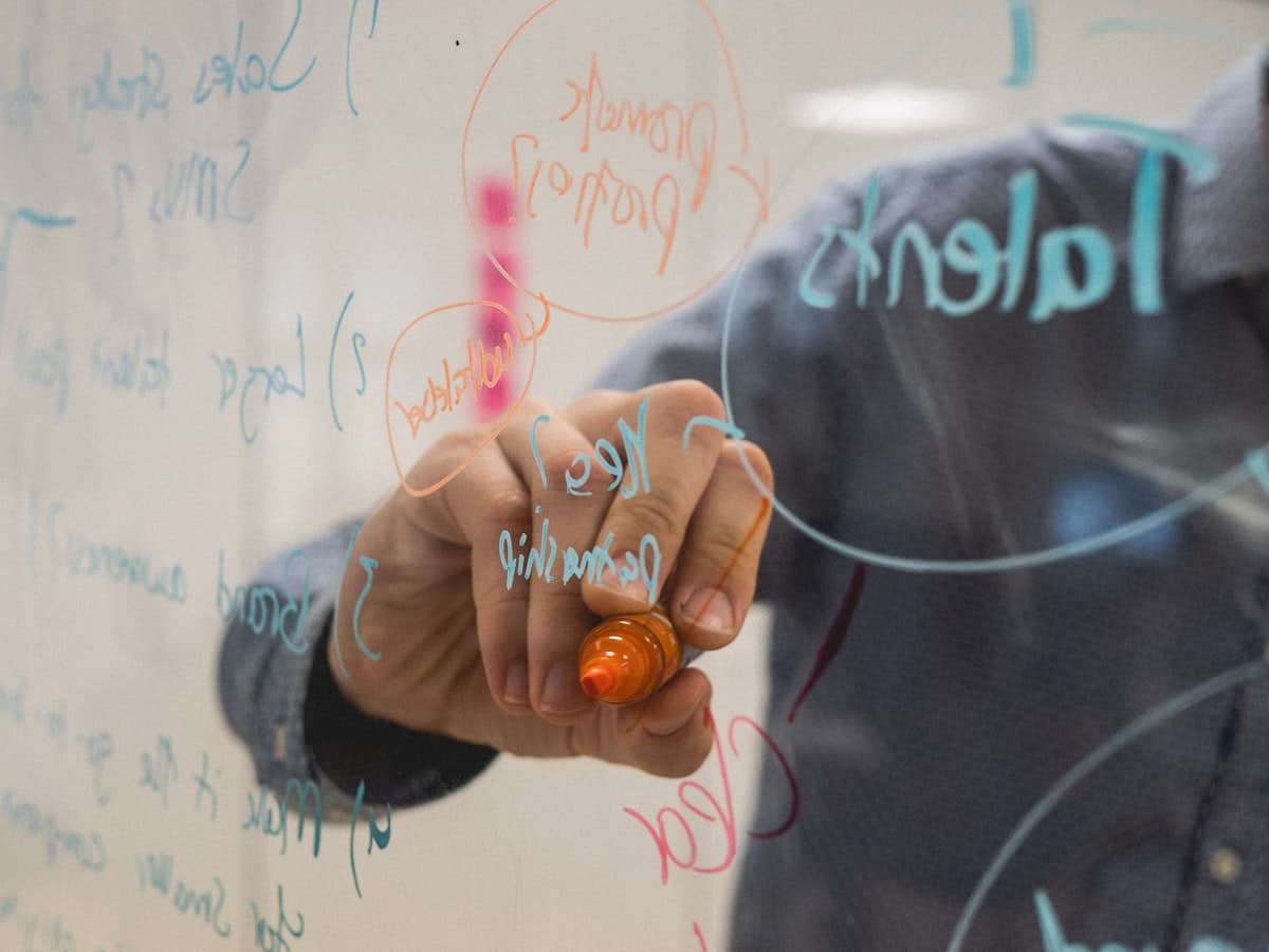 A strategist mapping site structure on a glass whiteboard